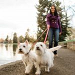 Julie K. walking 2 white dogs along pond