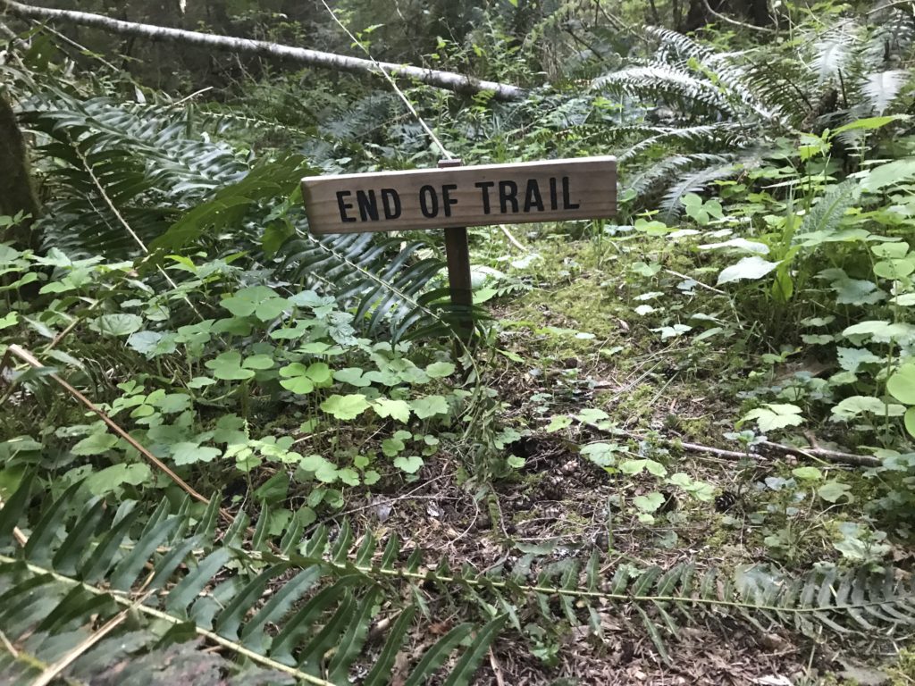 "end of trail" sign in the forest