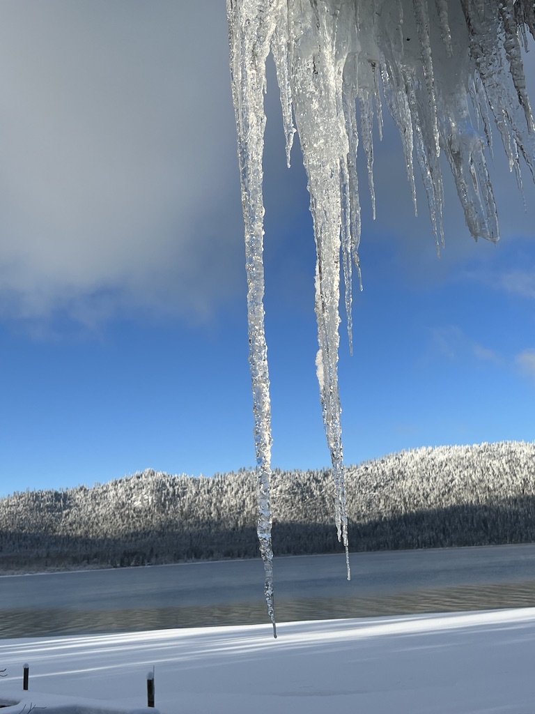 Large icicle hanging over lake and blue sky