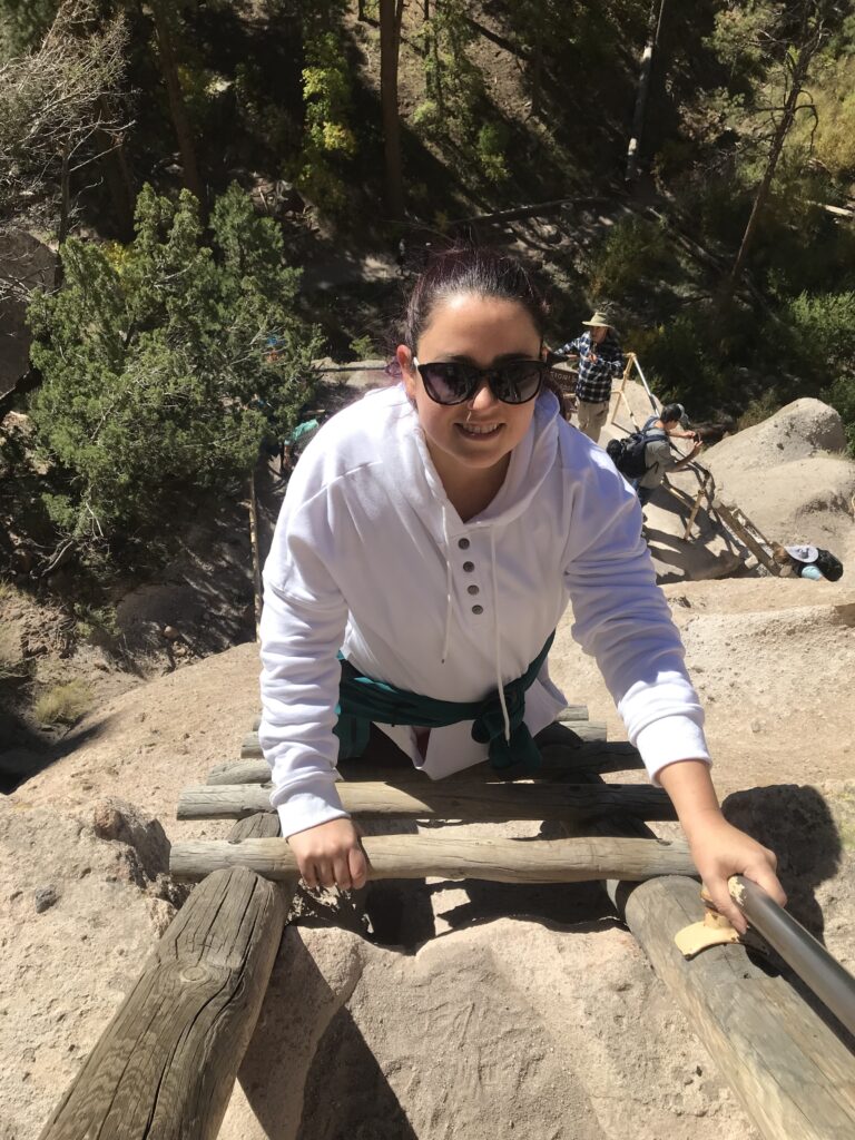 C climbing down a steep wooden ladder at Bandelier National Monument