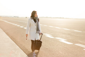 Julie K walking on tarmac with suitcase